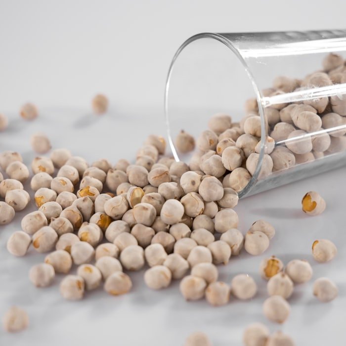 Cream coloured chickpeas spilling from a glass